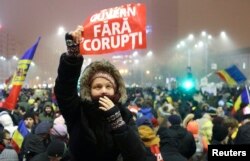 FILE - A woman holds up a sign that reads "Government without corruption" during a demonstration of thousands of Romanians against their government in Bucharest, Feb. 6, 2017.