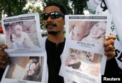 FILE - A member of the Islamic Defenders Front (FPI) holds up posters protesting against films in Jakarta, Sep. 28, 2010. The gay and lesbian community in Indonesia faces discrimination.