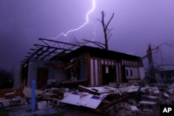 FILE - Lightning illuminates a house after a tornado touched down in Jefferson County, Ala., damaging several houses in Birmingham, Dec. 25, 2015.