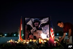 FILE - A man lays flowers next to a photo of James Foley, the freelance journalist killed by the Islamic State group, during a memorial service in Irbil, Iraq, Aug. 24, 2014.