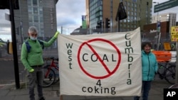 Demonstran membentangkan spanduk yang berisi penolakan terhadap tambang batu bara di West Cumbria, Inggris, dalam aksi protes yang berlangsung di tengah perhelatan konferensi iklim PBB di Glasgow, Skotlandia, pada 2 November 2021. (Foto: AP/Scott Heppell)