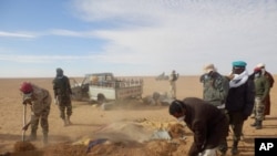 FILE - Volunteers and officials dig graves to inter the bodies of migrants who died of thirst after their the truck they were traveling in, seen rear, broke down while attempting to cross the Sahara Desert north of Arlit, Niger, Oct. 30, 2013. 