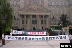 FILE - Residents hold banners outside the high court where Wen Qiang, the former municipal justice chief, was sentenced to death in Chongqing municipality. Simplified characters such as these were introduced in the mainland as part of a literacy campaign.