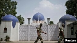 Dua orang penjaga keamanan India berjalan di depan pintu gerbang utama perwakilan Pakistan di New Delhi, India, 19 Agustus 2014. (Foto: dok). 