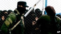 FILE - In this March 31, 2019 photo, women speak to guards at the gate that closes off the section for foreign families who lived in the Islamic State's so-called caliphate, at al-Hol camp in Hasakeh province, Syria. 