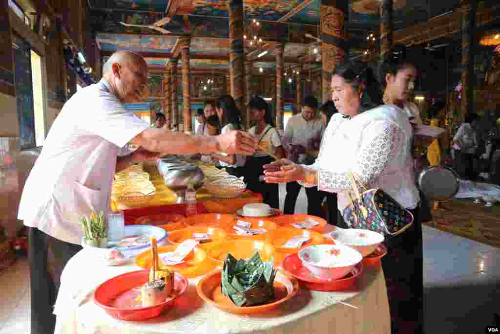 ប្រជា​ពលរដ្ឋម្នាក់​ទទួលទឹកមន្តពីតាអាចារ្យ នៅ​​​ក្នុង​ថ្ងៃ​​កាន់​បិណ្ឌ​ទី​១៣ នៃ​ពិធី​បុណ្យ​ភ្ជុំ​បិណ្ឌ​នៅ​រាជធានី​ភ្នំពេញ នៅ​ថ្ងៃទី​២៦​ ខែ​កញ្ញា ឆ្នាំ​២០១៩។ (កាន់ វិច្ឆិកា/VOA)