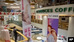FILE - A security officer wearing a face mask gives stands in a shopping mall with a number of stores that remained closed in Beijing, Feb. 3, 2020. 