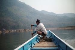 FILE - A local villager drive a boat where the future site of the Luang Prabang dam will be on the Mekong River, outskirt of Luang Prabang province, Laos, Feb. 5, 2020.