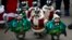 Visitors look at penguins wearing Santa Claus (in red) and Christmas tree (in green) costumes during a promotional event for Christmas at an amusement park in Yongin, south of Seoul, South Korea, Dec.18, 2013. 