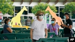 FILE - Patrons wearing masks to help prevent the spread of the new coronavirus wait in line to enter Zoo Miami, Sept. 15, 2020, in Miami. 
