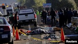 FILE - Police officers and rescue personnel stand near the bodies of people who were killed in a car crash on the outskirts of Puebla, Mexico, Dec. 12, 2017.