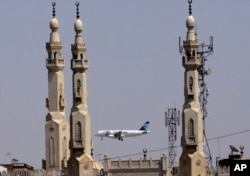 FILE - In this May 21, 2016, file photo, an EgyptAir plane flies past minarets of a mosque as it approaches Cairo International Airport, in Cairo, Egypt.