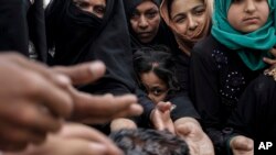 FILE - Mosul residents reach out for freshly baked cookies at a food distribution point inside western Mosul, Iraq, May 2, 2017. As Iraqi forces continue to make slow progress in the fight against the Islamic State group in Mosul, food supplies are running dangerously low for civilians trapped inside militant-held territory and those inside recently retaken neighborhoods.