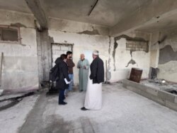 Ahmed Hashem was displaced from his home in Idlib, Syria, several times. Here, he speaks to Heather Murdock and Halan Akoiy in a complex refugees now occupy after it was abandoned by IS militants, in Raqqa, Syria, Feb. 23, 2020. (Hamodi JwanKojo/VOA)