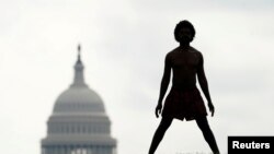 FILE - With the dome of the US Capitol in the background, a homeless man named Damu stretches on the National Mall in Washington, May 27, 2020. 