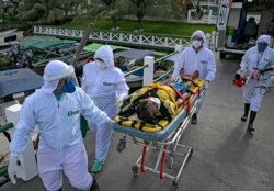 Medical personnel in protective gear transport a coronavirus patient to an ambulance boat, on Marajo island, Para state, Brazil, May 25, 2020.
