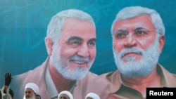 Sebuah mural yang menunjukkan wajah Jenderal Qassem Soleimani dan pemimpin komando milisi Irak Abu Mahdi al-Muhandis, terpampang di salah satu area di Baghdad dalam foto yang diambil pada 3 Januari 2021. (Foto: Reuters/Thaier Al-Sudani)