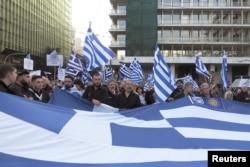 FILE - Protesters hold a Greek flag during a rally against the use of the term "Macedonia" in any settlement to a dispute between Athens and Skopje over the former Yugoslav republic's name, in Athens, Greece, Feb. 4, 2018.