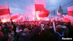 Protesters carry Polish flags and National Radical Camp flags during a rally, organized by far-right, nationalist groups, to mark 99th anniversary of Polish independence in Warsaw, Nov. 11, 2017.