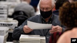 មន្រ្តី​ការិយាល័យ​បោះឆ្នោត​នៅ​សង្កាត់ Cobb កាន់​សន្លឹក​ឆ្នោត​ក្នុង​អំឡុងពេល​ធ្វើ​សវនកម្ម​កាលពី​ថ្ងៃទី១៦ ខែវិច្ឆិកា ឆ្នាំ២០២០ នៅ​ទីក្រុង Marietta រដ្ឋ Georgia។