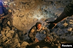 A civil defense member attempts to get out of a site hit at night by an airstrike in Saraqeb, in rebel-held Idlib province, Syria, Dec. 11, 2016.