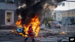 10일 우크라이나 수도 크이우에서 러시아의 폭격으로 파괴된 차에서 불길이 솟아오르고 있다.