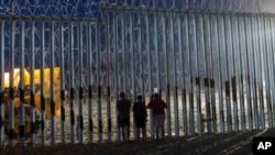 FILE - Children observe the movements of the US Border Patrol agents from the Mexican side where the border meets the Pacific Ocean, Tijuana, Mexico.