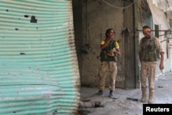 Syria Democratic Forces (SDF) fighters inspect a dead body of what they said was an Islamic State fighter inside a shop in Manbij, in Aleppo Governorate, Syria, August 7, 2016.