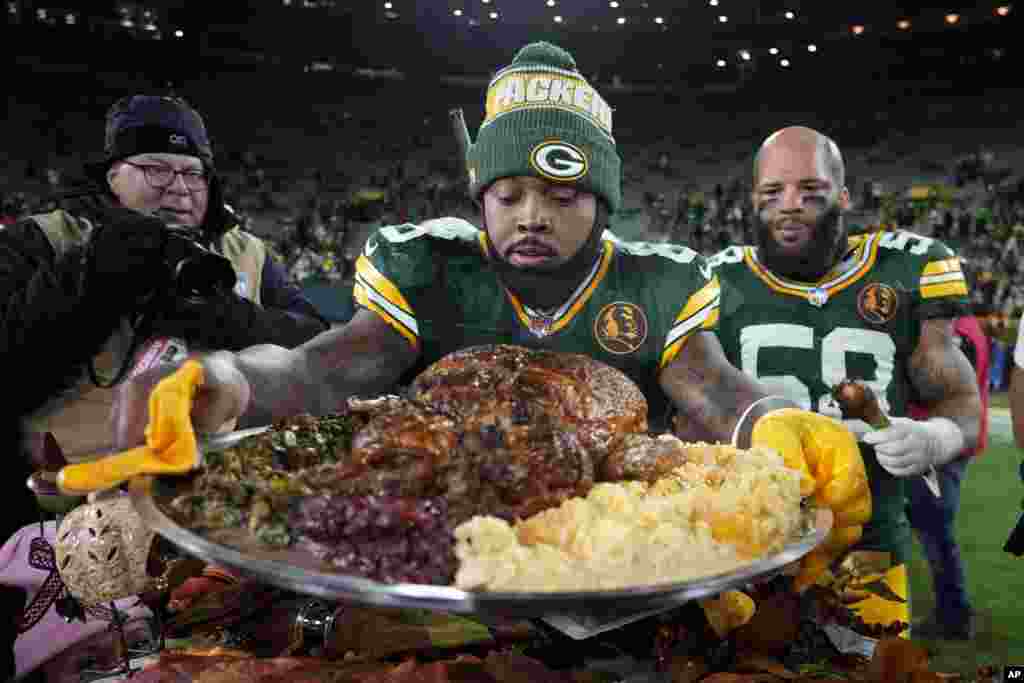 Green Bay Packers running back Josh Jacobs holds a plate of turkey after an NFL football game against the Miami Dolphins, November 28, 2024, in Green Bay, Wisconsin.