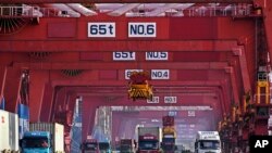 แฟ้มภาพ - รถบรรทุกขนถ่ายตู้สินค้าจากเรือขนส่งที่ท่าเรือชิงเต่า ในมณฑลชานตง ทางตะวันออกของจีน เมื่อ 11 ก.พ. 2567 (ภาพจากสำนักข่าวซินหัว)