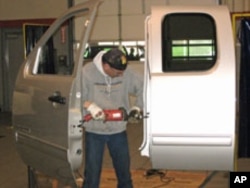 A worker prepares a GMC door to be attached to the lift.