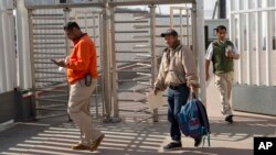 Carlos Catarldo Gomez, of Honduras, center, is escorted by Mexican officials after leaving the United States, the first person returned to Mexico to wait for his asylum hearing date, in Tijuana, Mexico, Jan. 29, 2019.