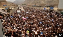 FILE - Afghan nationals prepare to cross the Torkham border post in Pakistan en route to Afghanistan, March 7, 2017.