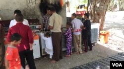 Warga Yazidi terlihat berkumpul di luar kuil Lalish, menikmati keteduhan, air dan es krim.
