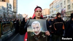 បុរស​អ៊ីរ៉ង់​ម្នាក់​កាន់​រូប​របស់​លោក Qassem Soleimani នៅ​ក្នុង​ពេល​ដង្ហែ​ក្បួន​សព​របស់​លោក Qassem Soleimani នៅ​ក្នុង​ក្រុង​តេហេរ៉ង់ ប្រទេស​អ៊ីរ៉ង់ កាលពី​ថ្ងៃទី៦ ខែមករា ឆ្នាំ២០២០។