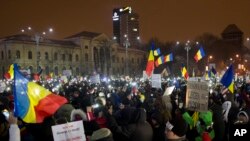 Protesters lit torches and wave flags as they gather outside the government building in Bucharest, Romania, Feb. 11, 2017. 