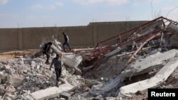 FILE - Youth inspect rubble of a damaged house after an airstrike on rebel-held Daraa al-Balad, Syria, April 7, 2017. 