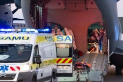 This French army photo provided April 4, 2020, shows coronavirus patients from Paris being loaded into ambulances in Clermont Ferrand the day before. France has moved patients around the nation to ease the strain on congested Paris hospitals.