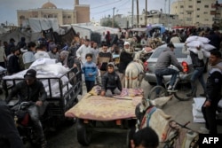 Seorang pria Palestina mengangkut karung bantuan kemanusiaan dengan kendaraan di luar pusat distribusi Badan Bantuan dan Pekerjaan PBB untuk Pengungsi Palestina (UNRWA), di Rafah di selatan Jalur Gaza pada 3 Maret 2024. (Foto: AFP)
