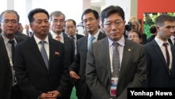 지난해 9월 러시아 블라디보스토크에서 열린 '동방경제포럼' 행사장에서 리용남 북한 대외경제상(왼쪽 2번째)과 윤상직 한국 산업통상자원부 장관(3번째)이 나란히 한 전시관 관계자의 설명을 듣고 있다. (자료사진)