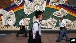 People wearing a protective face mask to help curb the spread of the coronavirus walk in Tokyo Thursday, July 2, 2020. Japan lifted a seven-week pandemic state emergency in late May, and social and business activity have since largely resumed. (AP…