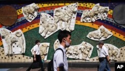 People wearing a protective face mask to help curb the spread of the coronavirus walk in Tokyo, July 2, 2020. 