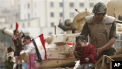 A soldier holds a crying girl from his armored vehicle just outside Tahrir Square in Cairo, Egypt, Feb 1, 2011