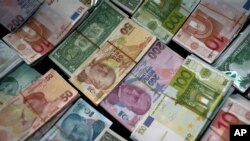 FILE - Turkish liras, center, featuring images of Turkish Republic founder Mustafa Kemal Ataturk, among other foreign currency, Istanbul, June 8, 2015.