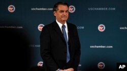 FILE - Brazilian President Jair Bolsonaro stands as he is applauded after speaking at the Chamber of Commerce in Washington, March 18, 2019. 