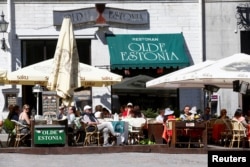 FILE - People sit in a restaurant in Tallinn, Estonia, May 31, 2018.