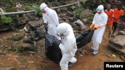 Health workers remove the body of a young man who local residents say died of Ebola in Monrovia, Liberia, Sept. 11, 2014.