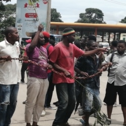 Protestsers carry a chain to be used to shutter the Malawi Electoral Commission office in Blantyre, Malawi. (Lameck Masina/VOA)