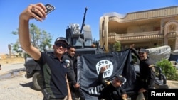 Members of the Iraqi Army are photographed with an Islamic State flag, claimed after fighting with Islamic State militants in western Mosul, Iraq, June 26, 2017.