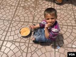Young Iraqi boy eating rice with tomato sauce and potatoes supplied in a Kurdish-run camp for Iraqis fleeing IS, April 11, 2016. (S. Behn/VOA)